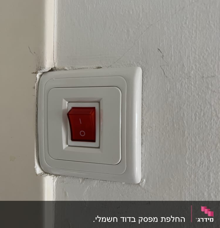 מתג חשמלי עם כפתור אדום על קיר לבן